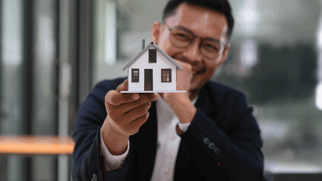 A man holding a house miniature.