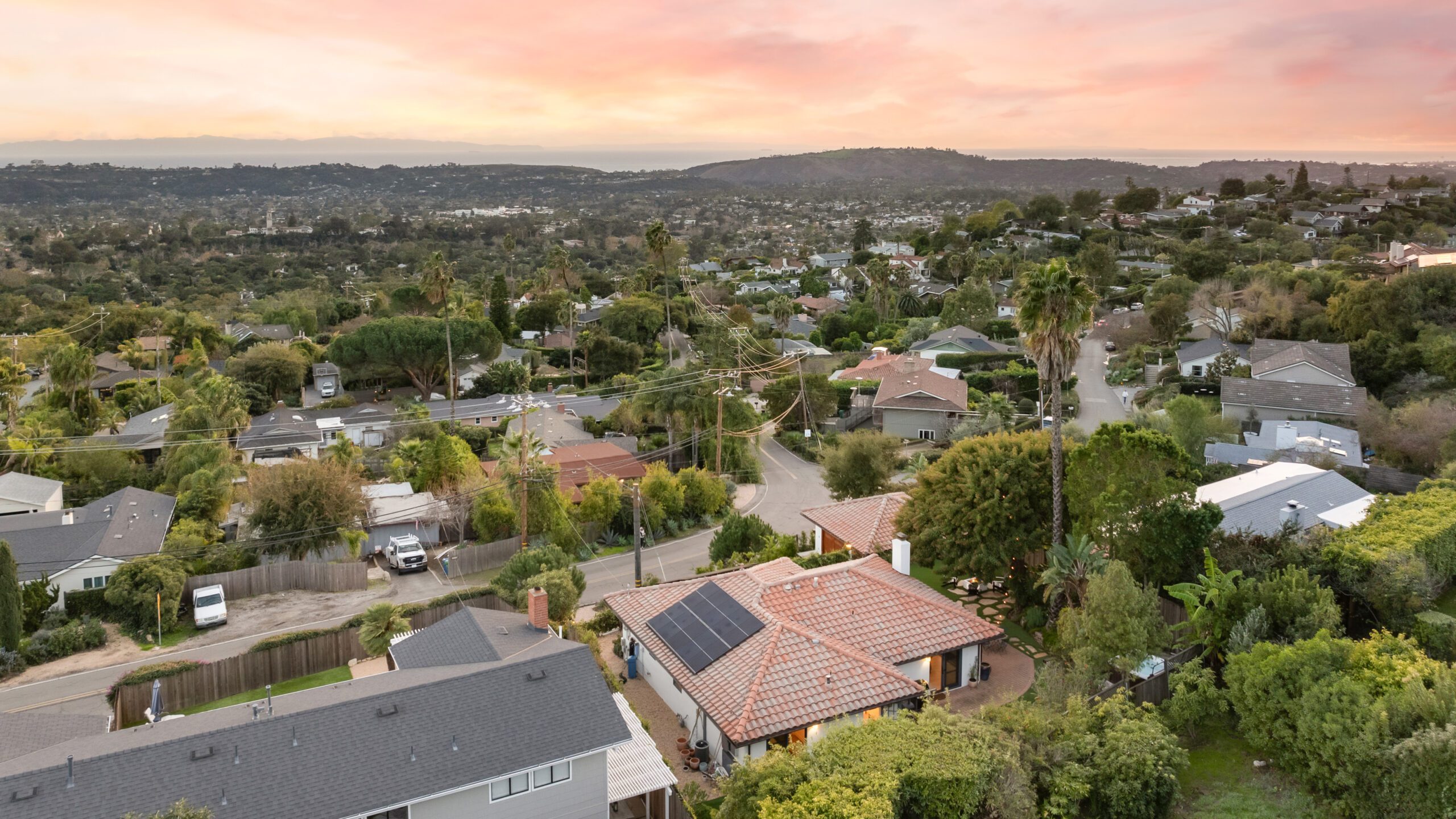 a view of the suburbs from the air at sunset, with buildings and a tree